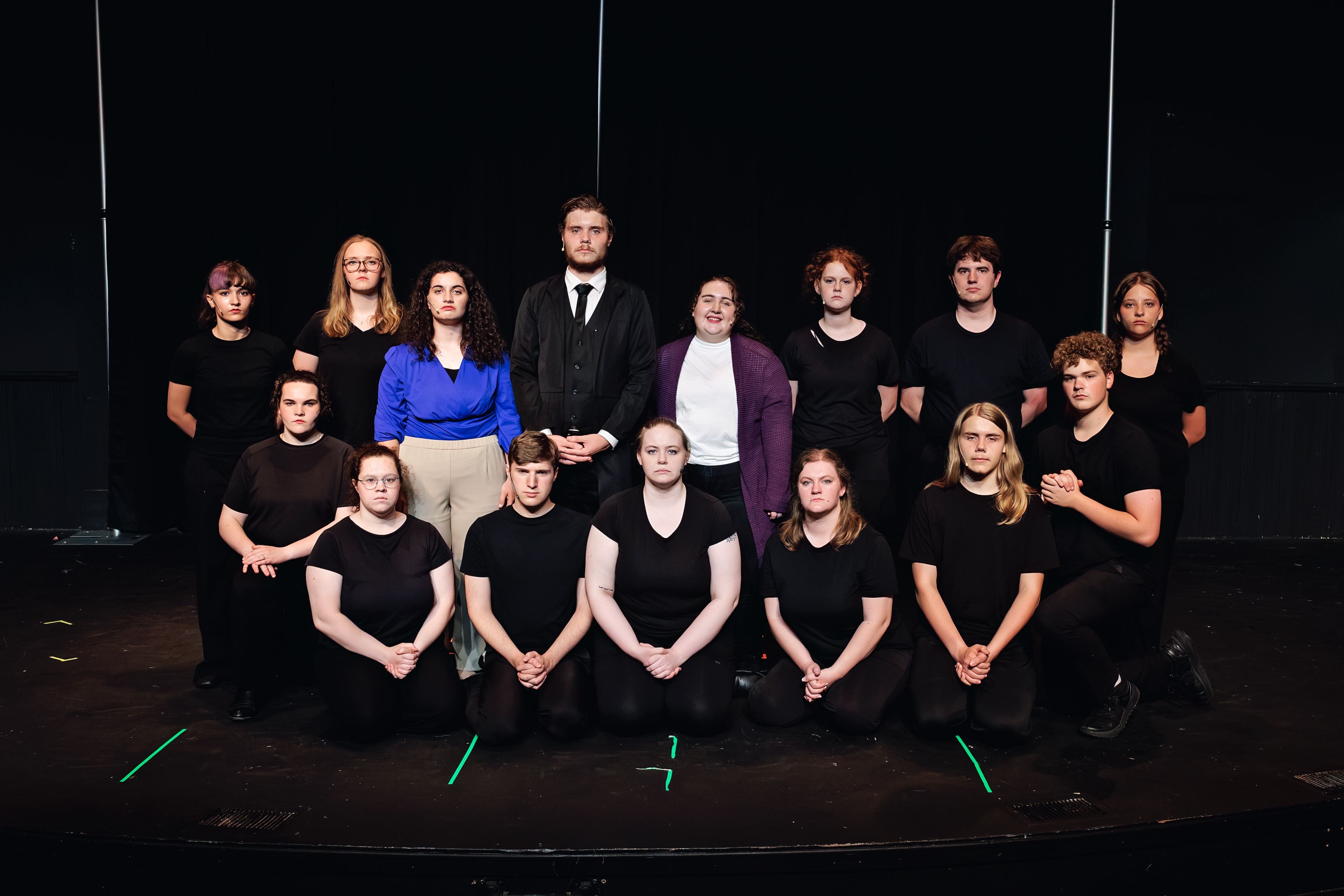The Two-Part Tragedy cast poses in standing and kneeling rows onstage.